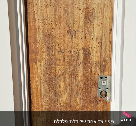 דלת עץ ישנה עם סימני שחיקה וידית חסרה